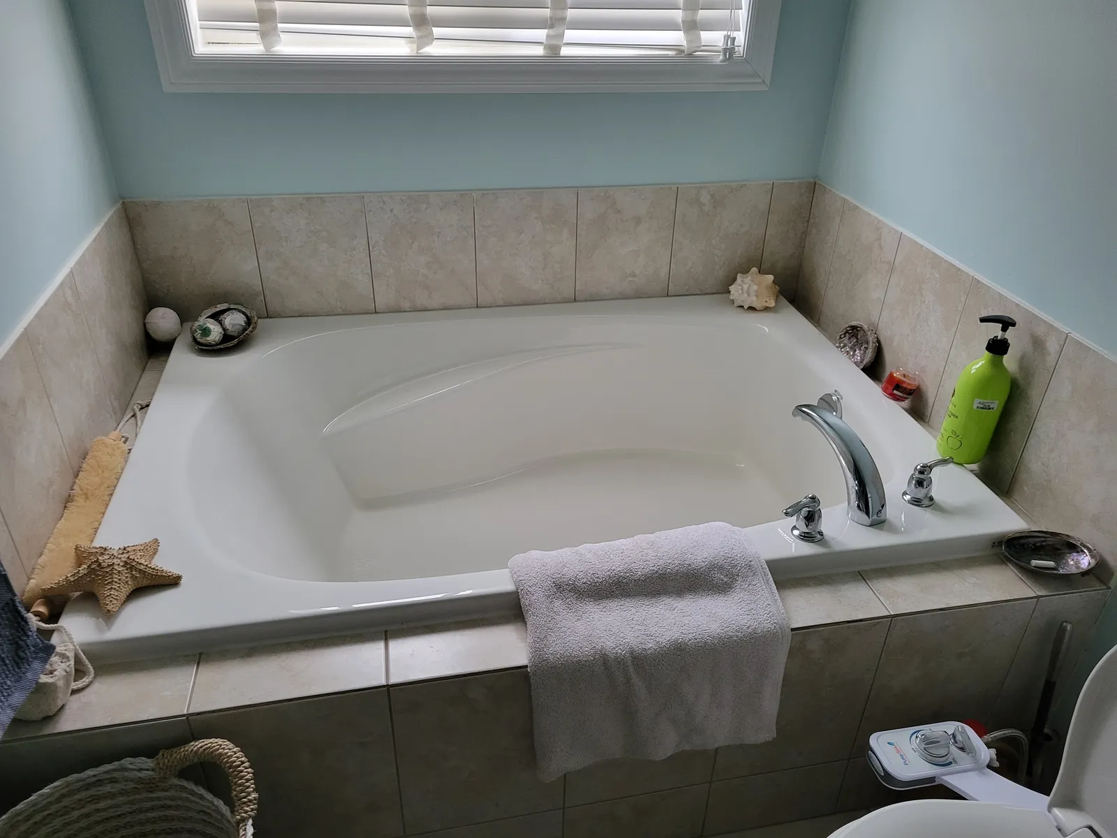 Dated beige-tiled bathroom in Richmond Hill before renovation, with a drop-in soaker tub and chrome deck faucet