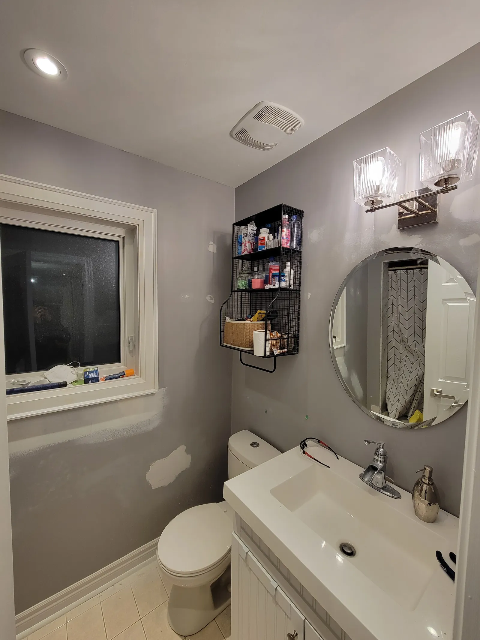 Freshly painted greige bathroom wall in Bradford with an oval mirror, chrome vanity lights and white sink