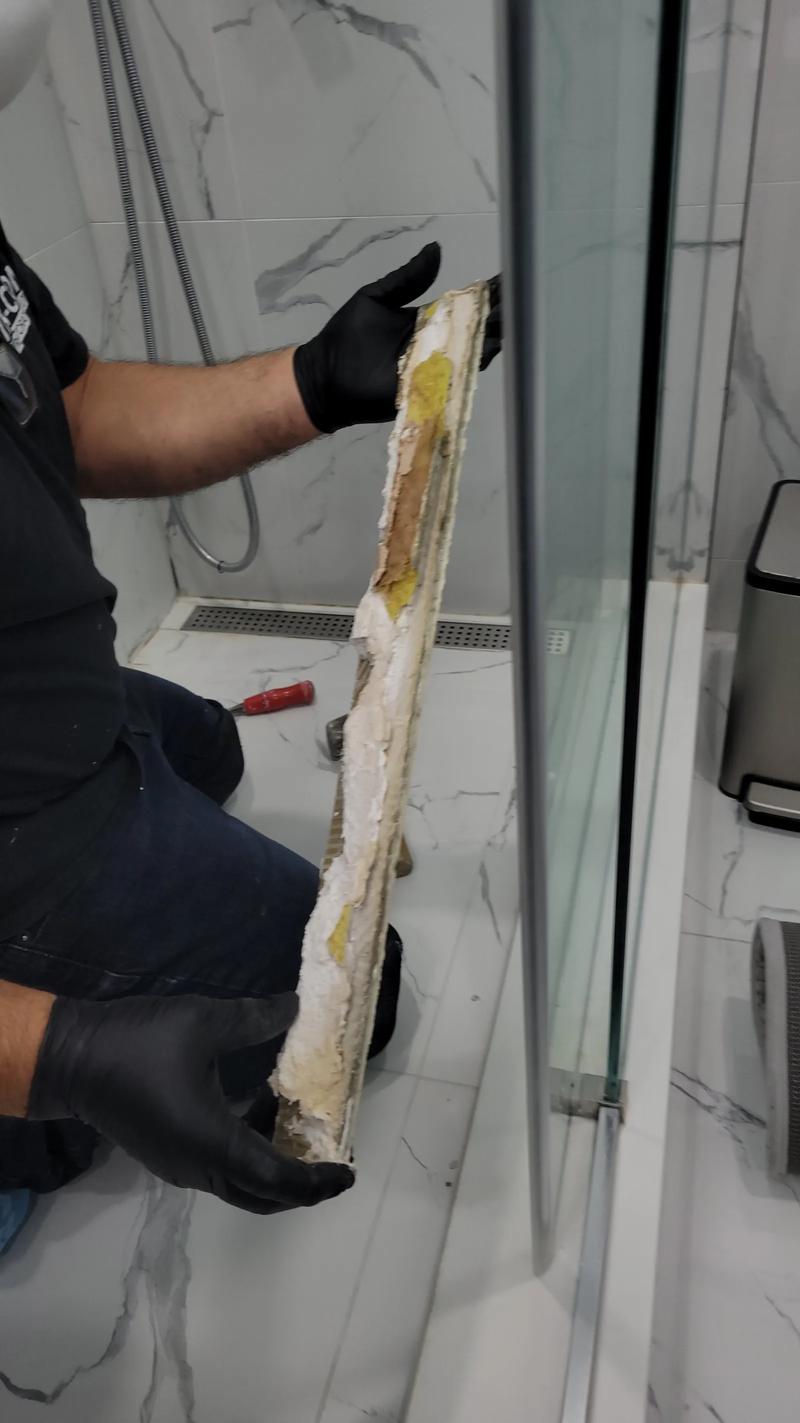 Removed shower curb section in Newmarket showing saturated, stained mortar inside from the leak