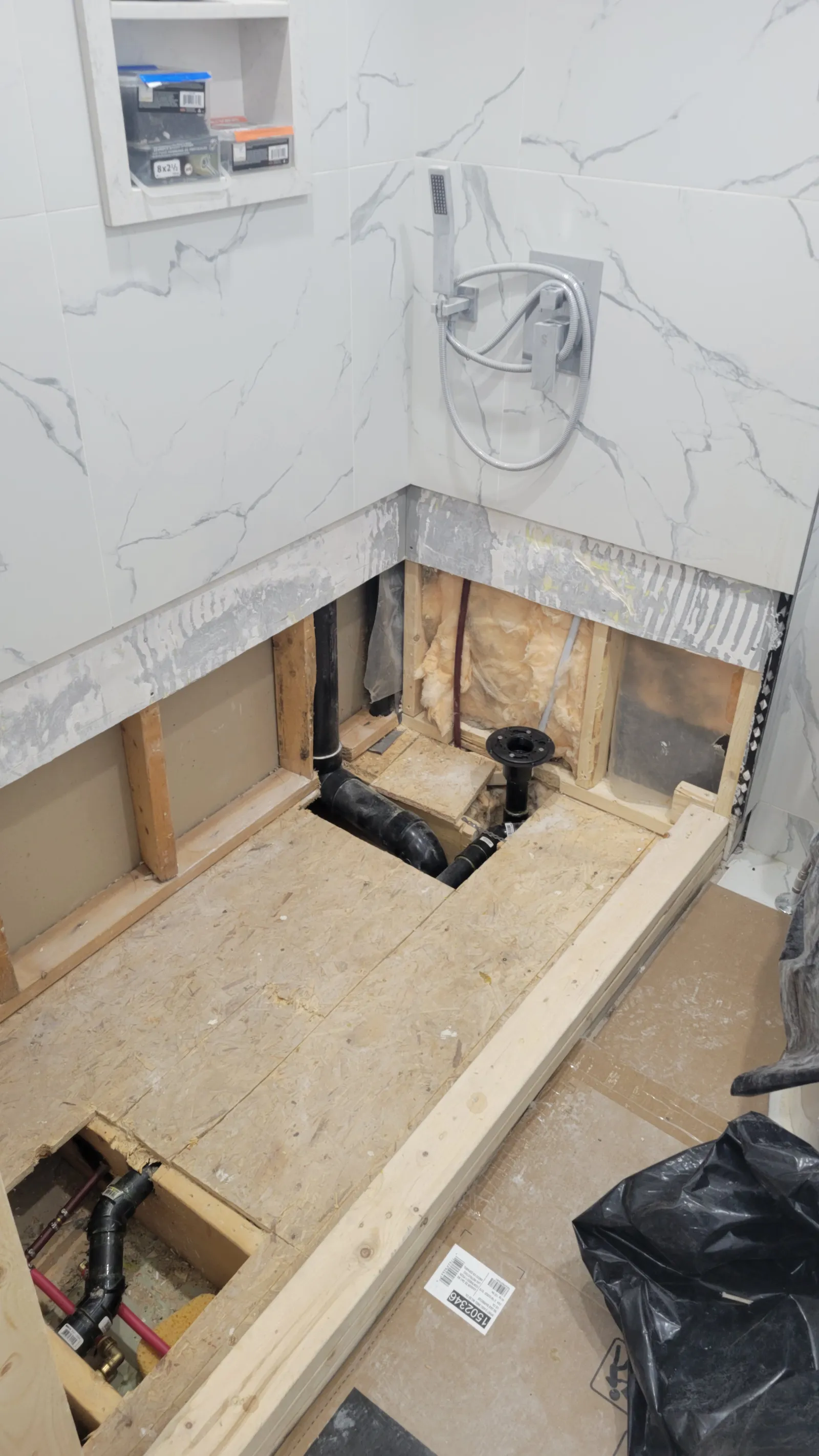 Shower subfloor in Newmarket opened to the joists showing the drain plumbing being redone after the leak